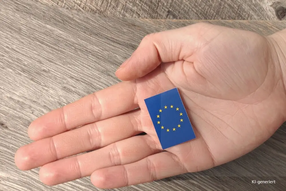 Titelbild: Wann ist eine Umsatzsteuer-ID für Selbstständige Pflicht? Hand liegt auf Tisch und hält ein EU-Zeichen in der Hand.