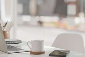 Headerbild für Kleinunternehmerregelung 2024: Schreibtisch mit Laptop, Tasse und Handy.