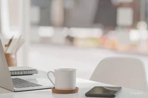 Headerbild für Kleinunternehmerregelung 2024: Schreibtisch mit Laptop, Tasse und Handy.
