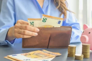 Headerbild Steuerglossar Soll-Ist-Versteuerung. Frau zieht 50 EUR Scheine aus einem Geldbeutel.